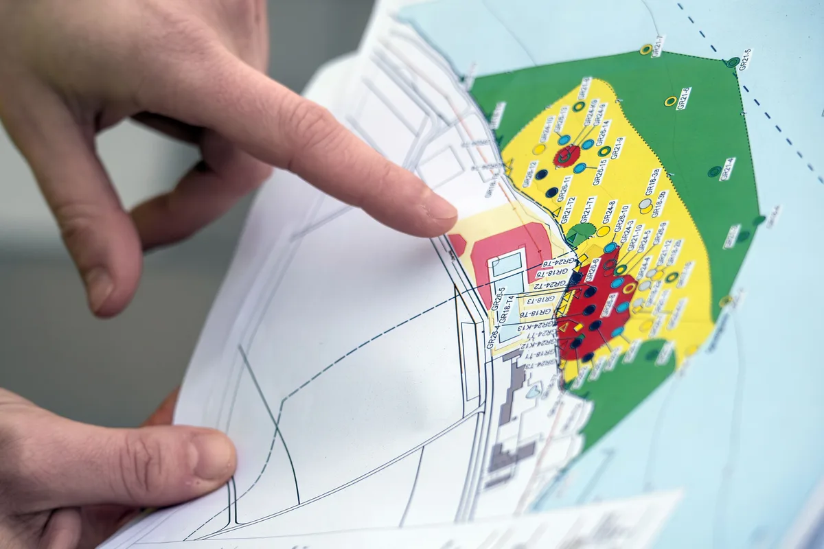 Man sieht eine Hand, die die Karte mit den verschiedenen Belastungsstufen vor dem Strandbad anzeigt.